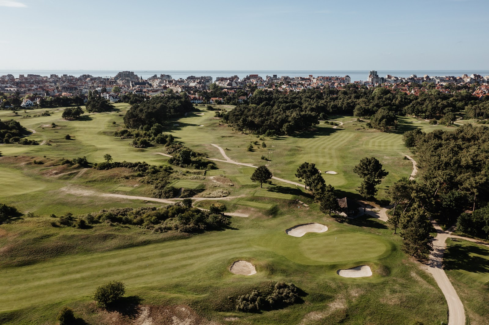 Wooded parkland golf course in Belgium under a soft northern sky