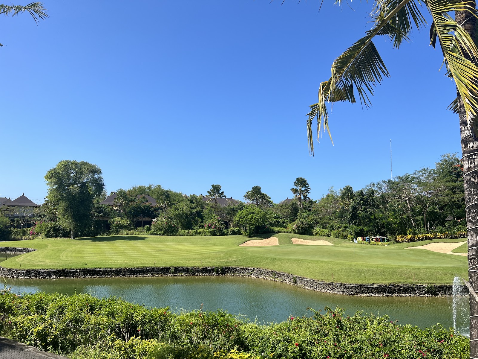 Golf course in Bali, Indonesia, tropical fairway with palms and volcanic hills beyond