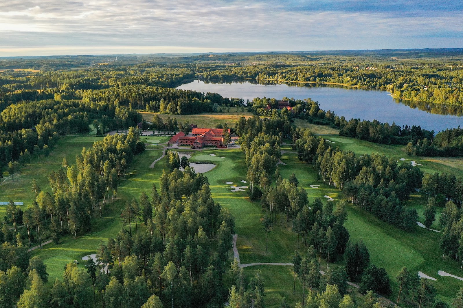 Linna Golf fairways winding through pine and birch forest beside a lake in southern Finland